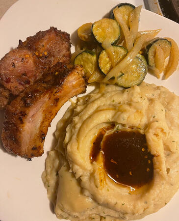 Slow-cooked ribs and garlic mashed potatoes, served with dijon zucchini and onions