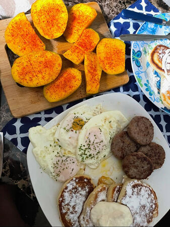 Japanese pancakes served with fried eggs, sausage, and fresh mango